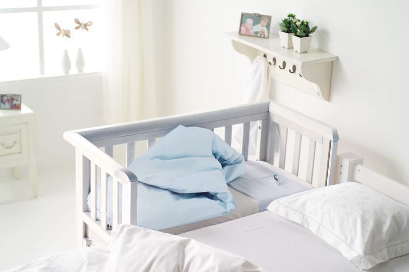 baby crib next to bed